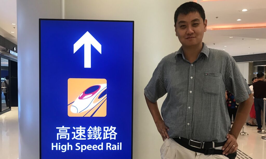 David Feng with a signpost showing High Speed Rail